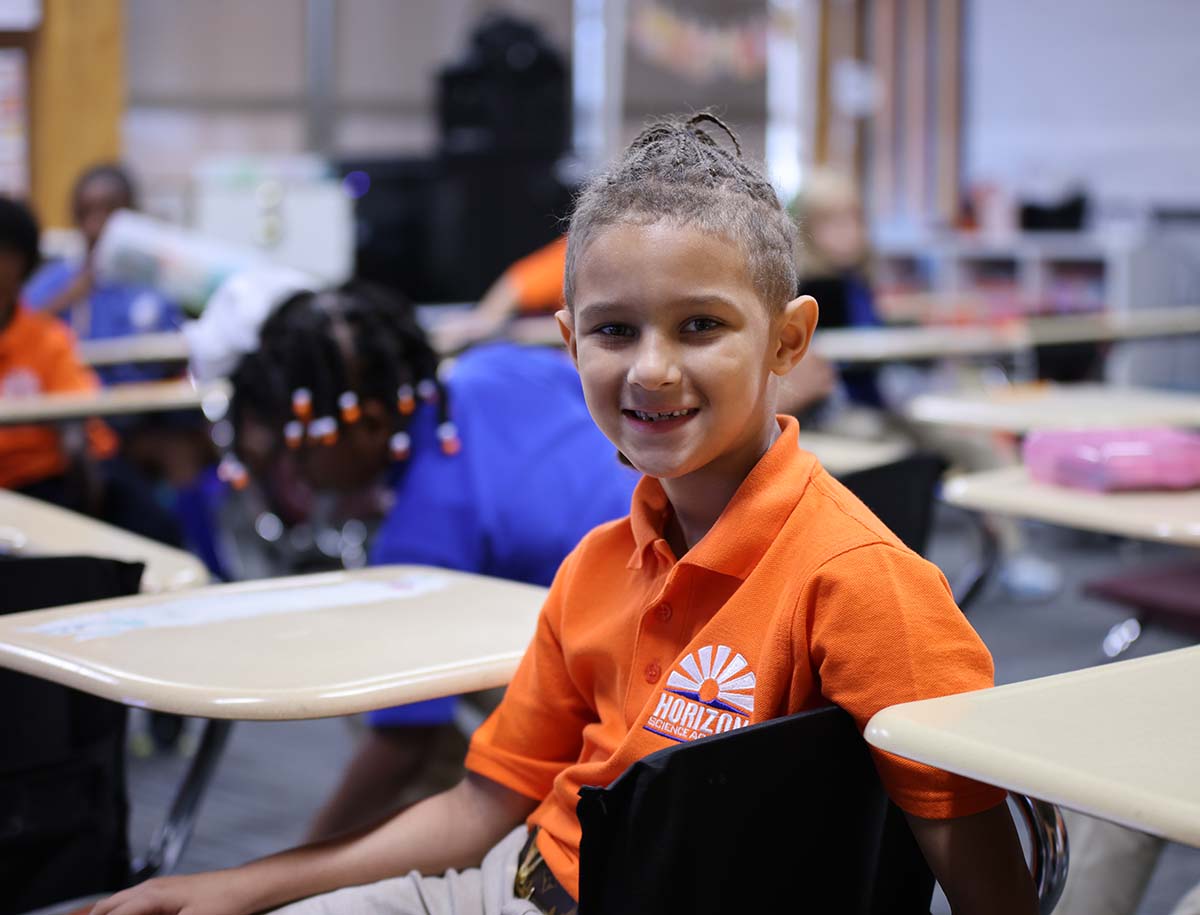 Elementary student smiling and posing together in a classroom.